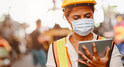 femme masqué et casquée devant une tablette