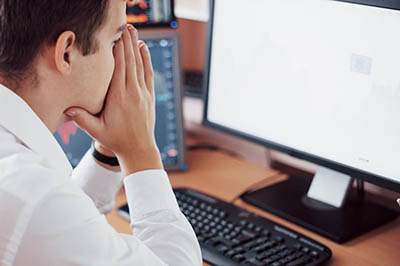 homme dépité devant un écran d'ordinateur