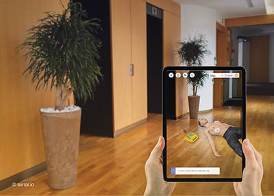 couloir avec 2 portes d’ascenseur et deux mains tenant une tablette montrant une scène en réalité augmentée