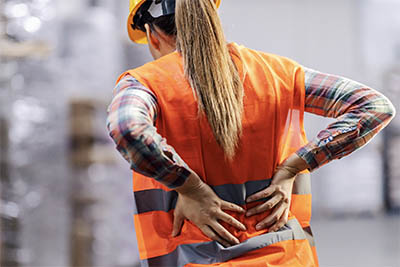 femme avec gilet orange se tenant le dos