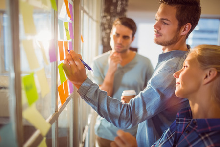 hommes et femme devant un tableau vitré avec des post-it