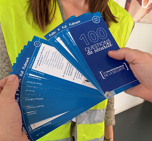 personne tenant des fiches en éventail avec l'inscription 100 questions de sécurité