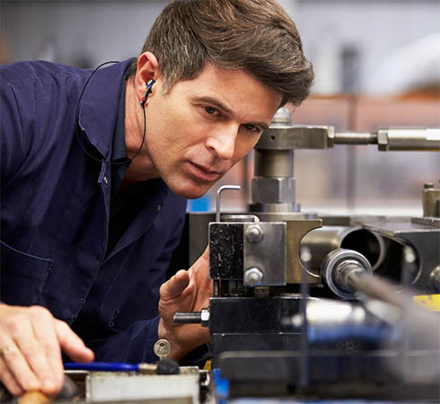 homme avec des protections auditives devant une machine outil