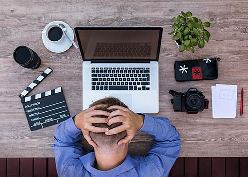 homme qui a sa tête dans les mains devant ses outils de travail