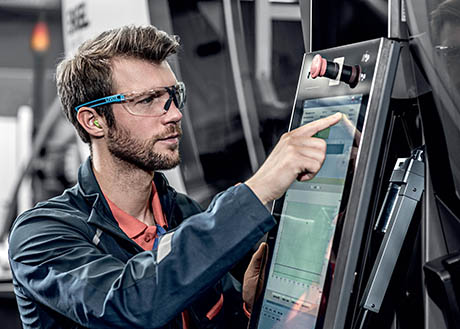 homme avec lunettes de sécurité devant machine outil
