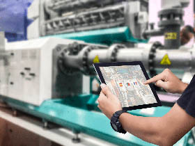 homme avec sa tablette devant une machine