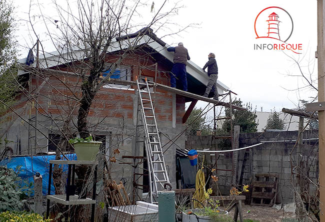 deux hommes sur un échafaudage bien penché qui travaillent devant une maison en travaux