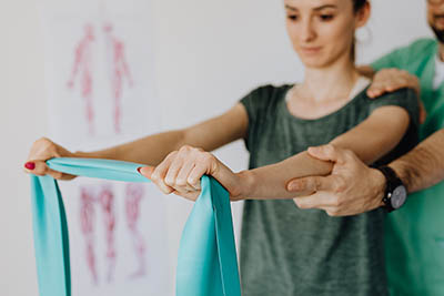 femme faisant un exercice de renforcement musculaire avec un kinésithérapeute